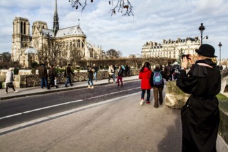 Tourists on Pont de l'Archevêché and Notre Dame Cathedral (Cathedrale Notre Dame de Paris) in the