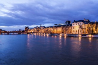 Seine River and Louvre Palace (Palais du Louvre) viewed from Pont des Arts at evening. Paris,