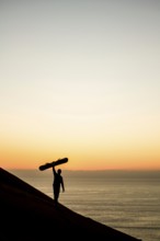 Silhouette of a sandboarder in Cerro Dragon at sunset, a sand dune located next to the city of
