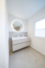 Minimalistic washing area with round LED mirror, double sink and large window, house renovation,