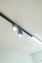 Black power rail with two LED spotlights as accent lighting under a white ceiling, house