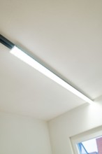Slim LED light strip on white ceiling next to a window, clear and modern, house renovation, energy