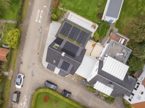 Aerial view of a residential building with PV system and neighboring buildings, well-kept gardens