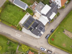 Aerial view of a residential area with house and photovoltaic, green gardens and traffic-calmed