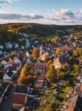 A village with a church in autumn, surrounded by colorful trees and hills, Deufringen, Aidlingen,