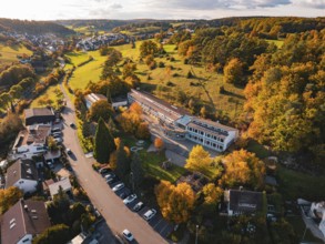 A school building between colorful autumn trees and hills in a village, Deufringen, Aidlingen,