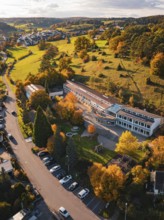 Large school building surrounded by autumn trees and meadows in a village, Deufringen, Aidlingen,
