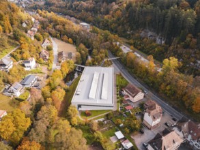 Sports hall located in an autumn landscape with surrounding forest and nearby roads, Walter Lindner