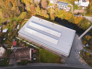 Flat sports hall in the midst of autumn surroundings with adjacent village and river, Walter