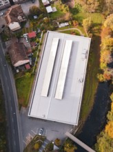 Aerial view of a sports hall with a flat roof surrounded by colorful autumn vegetation, Walter