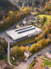 Modern sports hall in the midst of an autumn landscape with colorful trees and a small river,