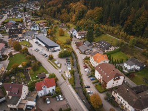 Aerial view of a village with autumn trees, roads, buildings and a small river, Calmbach, Bad
