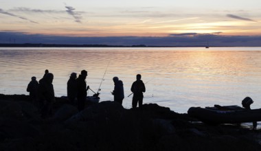Angler on the beach during sunset, an angler docks on the shore with his inflatable boat, Fehmarn