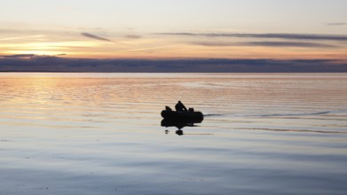 An angler docks on the shore with his inflatable boat and dog, Fehmarn Island, 18.10.2025, Fehmarn,
