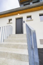 Stairway to the simple house entrance with dark door and warm light, house renovation, air