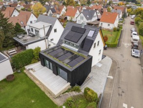 Angled aerial view of a modernized house with photovoltaic on gable roof and green extension in a