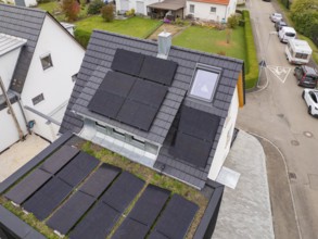 Close-up of anthracite-colored gable roof with several PV fields, skylight and fireplace, house