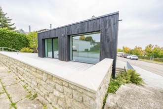 Contemporary extension with large glass front and terrace over a natural stone wall, house