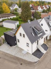 Drone view of a single-family house with modern extension and solar panels in a quiet settlement in