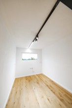 Narrow, bright room with light rail and oak floor, a window with connections at the back, house