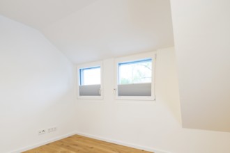 Bright room under the sloping roof with two windows and pleated blinds, house renovation, air