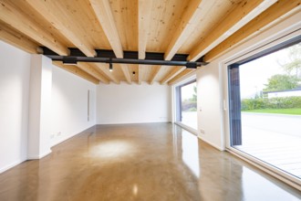 Large, modern room with wooden ceiling, black steel girders and polished concrete floor, open to