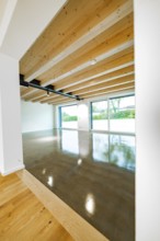Open space with wooden ceiling, steel girders and polished concrete floor, transition from parquet