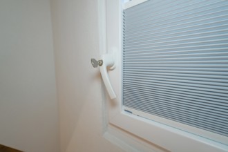 Detail of a lockable white window handle with integrated blind, house renovation, climate