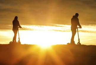 E-scooter drivers ride across a dike on the island of Fehmarn at sunset, 13.10.2025, Fehmarn,