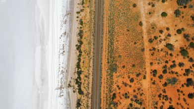 Train tracks divide a saltlake and the desert in the Australian outback, photograped with a drone