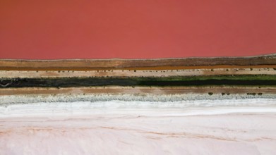 Pink lake next to the xoast, divided by streams and streets, photograped with a drone