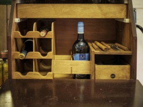 A fox hunting tack trunk with individual cigars, a bottle of sherry and an opener