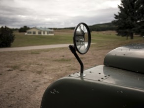 A cracked review mirror reflects a hood ornament on a 1950's Series One Land Rover on August 8,