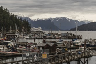 Marina with numerous boats, scenic mountain backdrop, and a cloudy sky in Horseshoe Bay, West