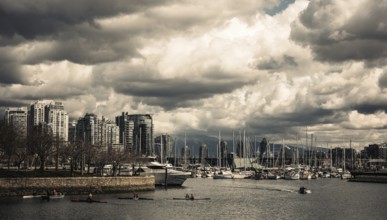 A vibrant cityscape with boats in the harbor beneath dramatic clouds in Vancouver, British