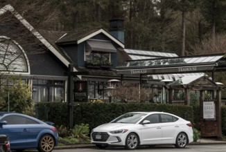 A teahouse in Stanley Park with parked cars, surrounded by lush greenery and overcast skies in