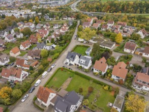 A panoramic view of a quiet suburban settlement with allotments and a winding highway in autumn