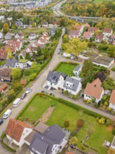 Suburban road with single-family houses and autumn gardens, a motorway in the background,