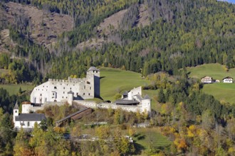 Medieval castle over autumnal forests and meadows in a sunny mountain landscape, Herbstenburg, Drau