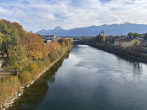 River through a city, autumn trees and mountains in the background under a clear sky, Drau, Drau
