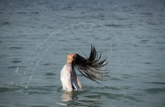 Young cute girl waving hair in the water