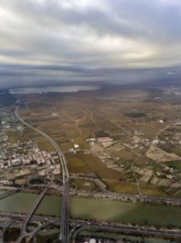 Turia flood canal with CV-500 road bridges, Albufera lagoon behind, aerial view, Valencia, Spain