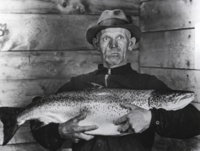 Fisherman with large salmon, presumably a king salmon or quinnat (Oncorhynchus tshawytscha), ca.