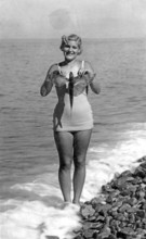 Woman on the beach in a bathing suit with flying fish, presumably swallowfish (Exocoetus volitans),