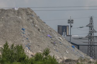 Chimneys, which are not far from factories, rise over mountains of waste. The sky is cloudy and