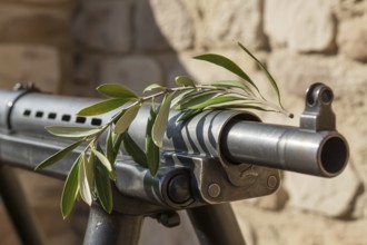 Olive branch placed over a machine gun barrel. Symbol of peace and anti-violence. Generative ai, AI