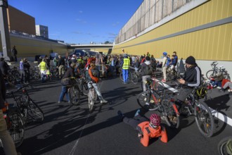 Cyclists wait to continue their journey. Meanwhile, a woman wearing a helmet is lying on the
