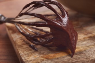 Metal whisk, close-up with chocolate dough, baking, structure and consistency, homemade, top view,