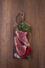 Freshly sliced lamb chops, with herbs and vegetables, on a wooden board, ready to cook, on a wooden