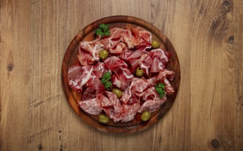 Assortment, sliced meat appetizer, prosciutto, salami and ham, with olives, on a wooden board,